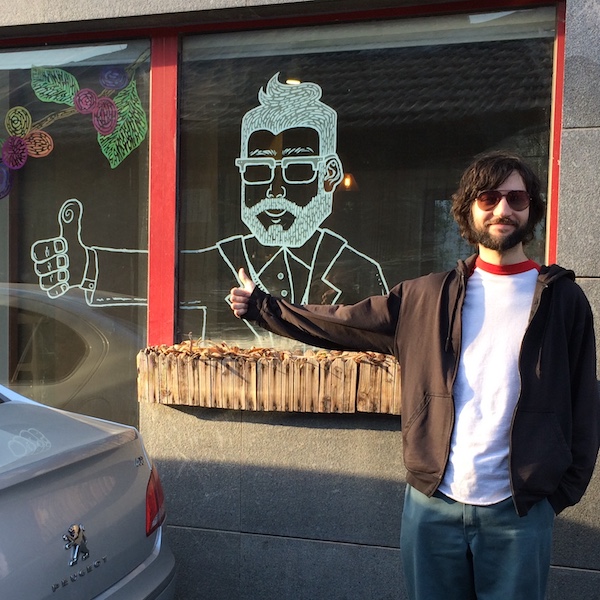 Josh giving a thumbs-up in front of a coffee shop